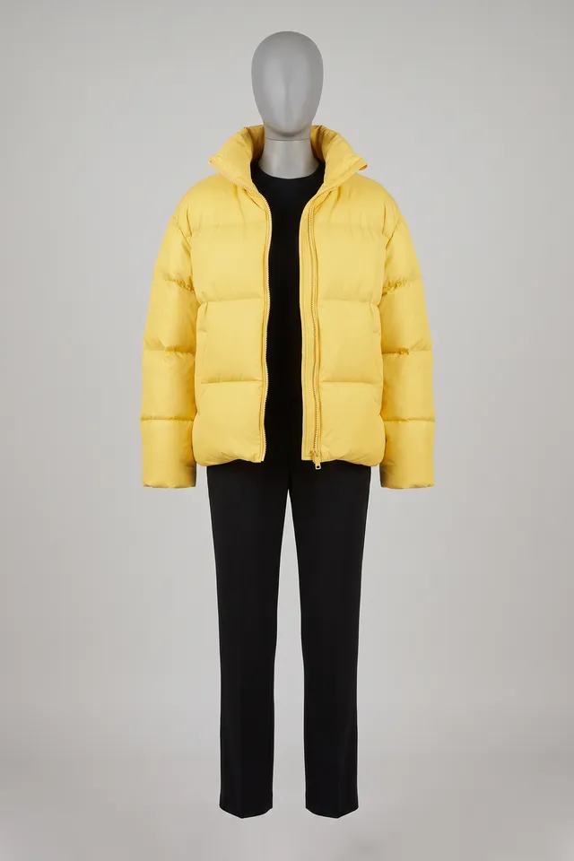 Canary-yellow oversized puffer jacket over black pants on a headless dress form