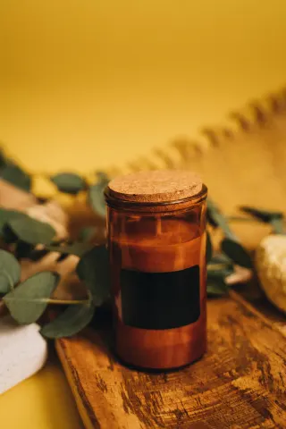 Amber glass candle jar with a cork lid and a plain black label