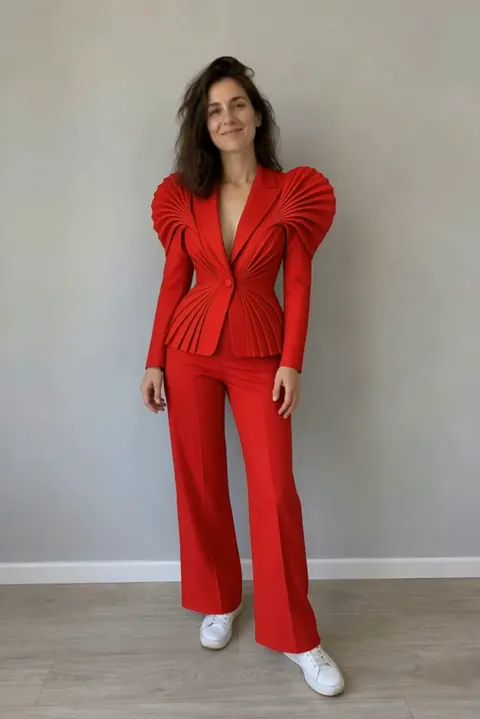 Actual Aisma result: The same turn in a scarlet sculptural pleated pantsuit.