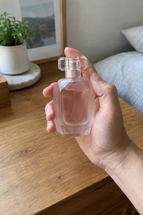 Actual Aisma result: The same hand turning a frosted blush-pink faceted bottle.